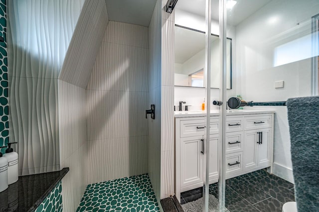 bathroom with vanity, tiled shower, and tile walls