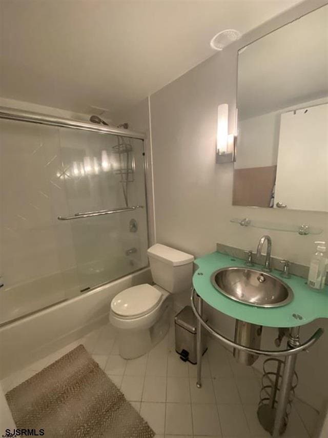 full bathroom featuring tile patterned floors, sink, enclosed tub / shower combo, and toilet