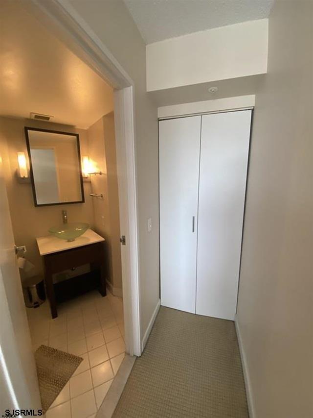 hall featuring light tile patterned floors and sink