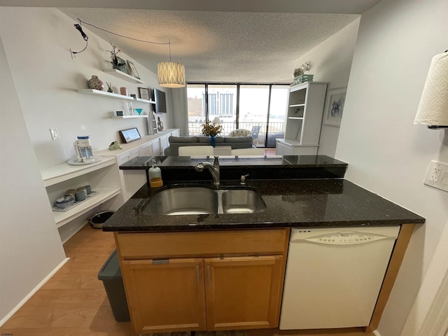 kitchen featuring sink, dark stone countertops, white dishwasher, light hardwood / wood-style floors, and a textured ceiling