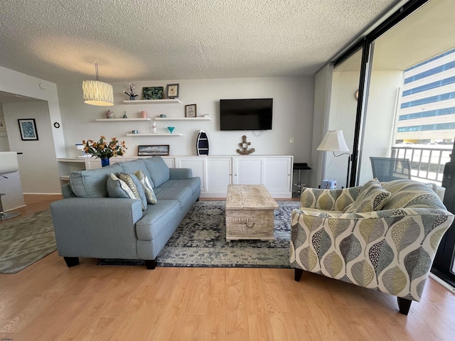 living room featuring a textured ceiling, light hardwood / wood-style flooring, and a wall of windows