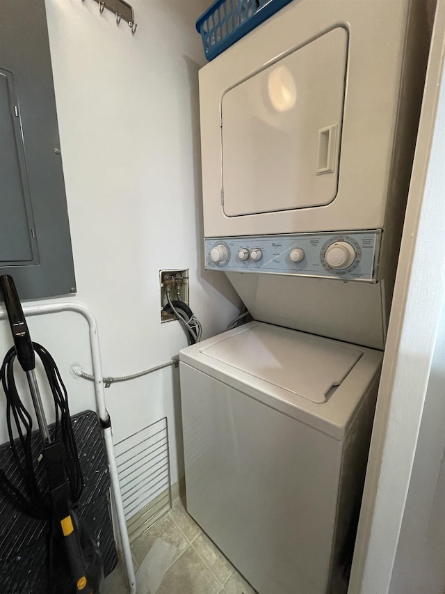 laundry room with electric panel, stacked washer / dryer, and light tile patterned flooring