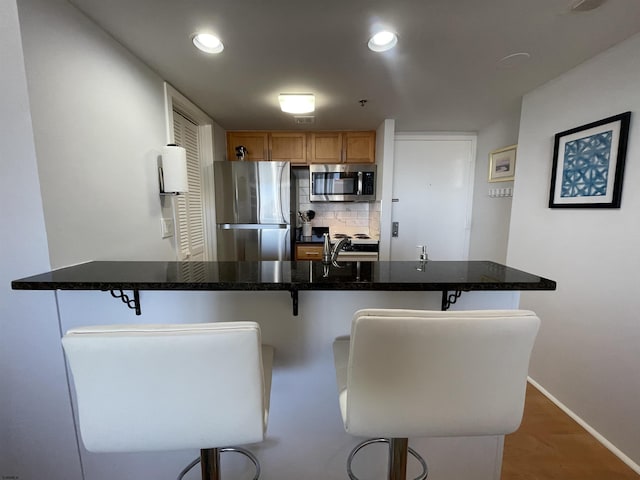 kitchen featuring decorative backsplash, a kitchen bar, sink, and appliances with stainless steel finishes