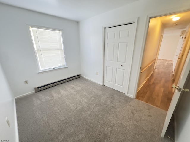 unfurnished bedroom featuring baseboard heating, a closet, and carpet