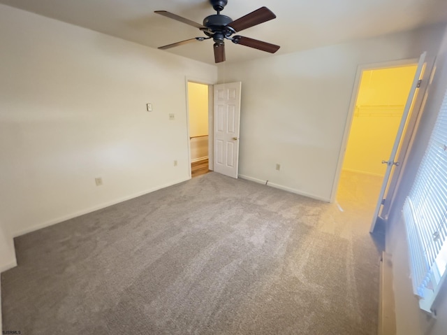 unfurnished bedroom featuring ceiling fan, a walk in closet, a closet, and carpet floors