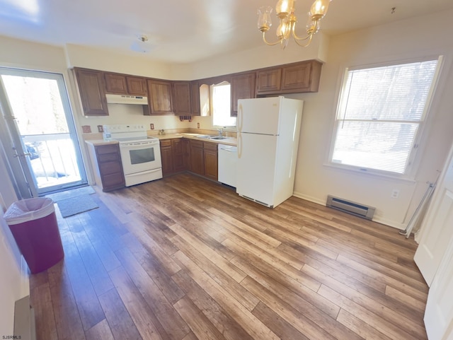 kitchen featuring white appliances, hardwood / wood-style flooring, a baseboard radiator, pendant lighting, and a notable chandelier