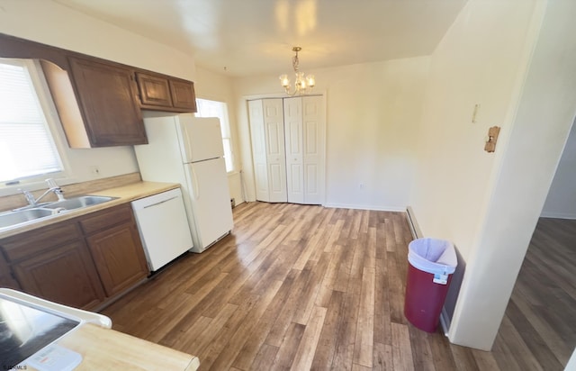 kitchen featuring white appliances, hardwood / wood-style flooring, a chandelier, decorative light fixtures, and sink