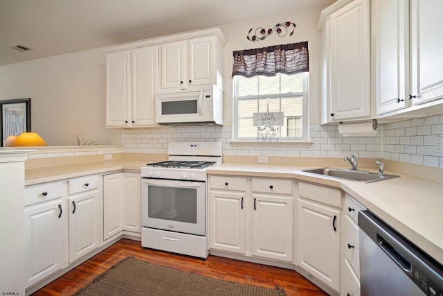 kitchen with white appliances, white cabinetry, dark wood-type flooring, and sink