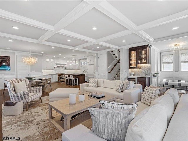 living room featuring coffered ceiling, crown molding, beam ceiling, an inviting chandelier, and hardwood / wood-style floors