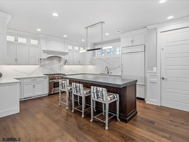 kitchen with pendant lighting, high quality appliances, backsplash, dark hardwood / wood-style floors, and white cabinetry