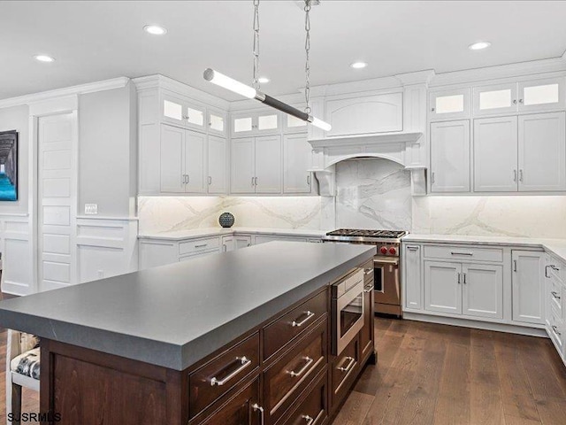 kitchen featuring white cabinetry, a center island, stainless steel appliances, dark hardwood / wood-style flooring, and pendant lighting