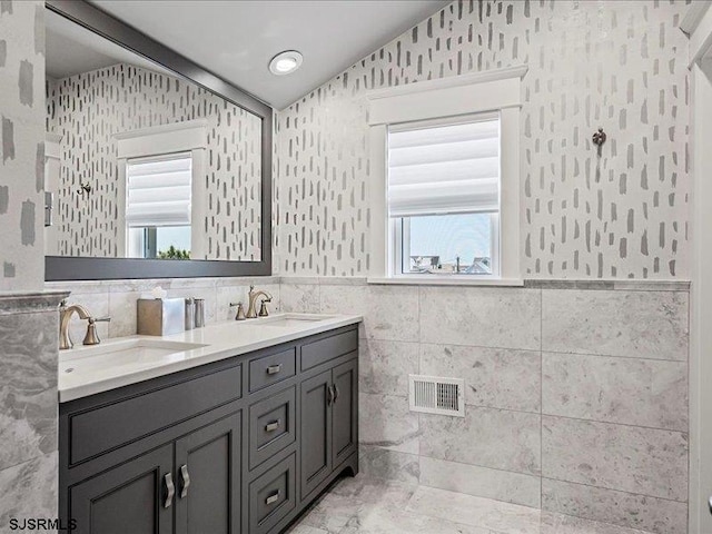 bathroom featuring vanity, a healthy amount of sunlight, and tile walls