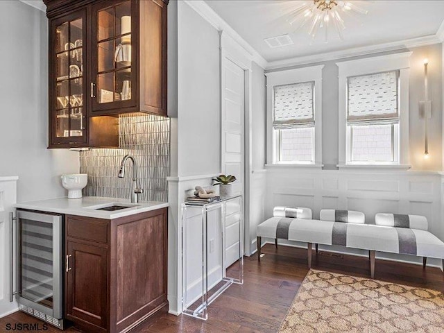 bar with dark brown cabinetry, sink, wine cooler, dark hardwood / wood-style flooring, and crown molding