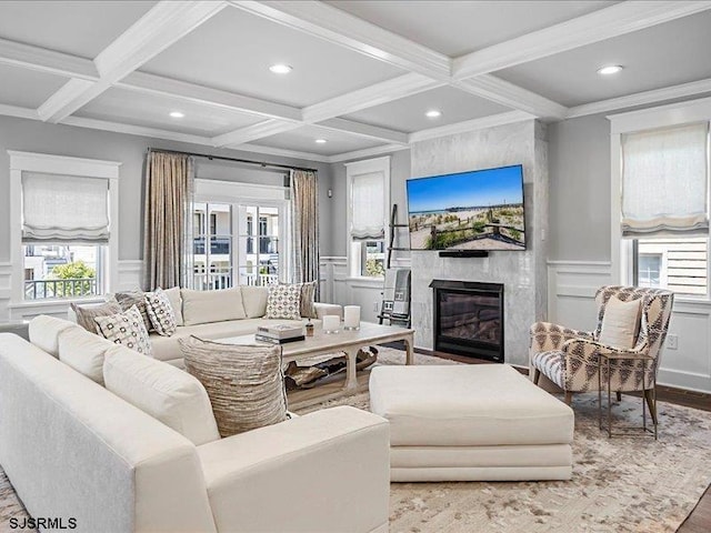 living room featuring coffered ceiling, crown molding, light hardwood / wood-style flooring, a premium fireplace, and beamed ceiling