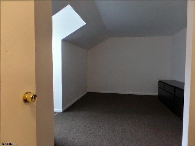 bonus room with dark colored carpet and lofted ceiling