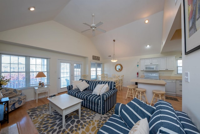 living room with hardwood / wood-style floors, ceiling fan, and high vaulted ceiling