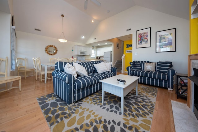 living room featuring ceiling fan, vaulted ceiling, and light wood-type flooring