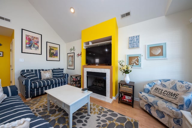 living room featuring hardwood / wood-style floors, a high end fireplace, and vaulted ceiling