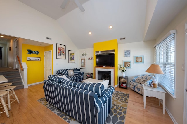 living room with ceiling fan, wood-type flooring, and vaulted ceiling