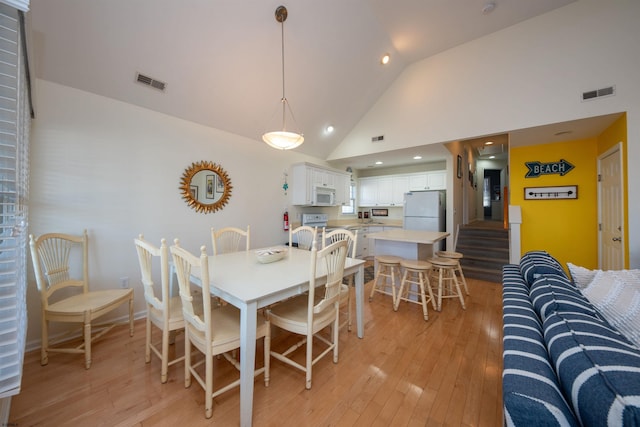 dining room featuring light hardwood / wood-style floors and high vaulted ceiling