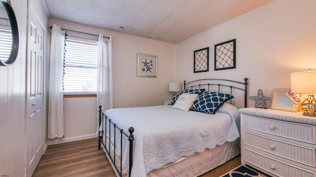 bedroom with a textured ceiling, dark hardwood / wood-style floors, and a closet