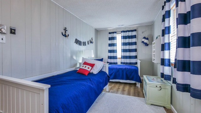 bedroom with light hardwood / wood-style floors, multiple windows, and wooden walls