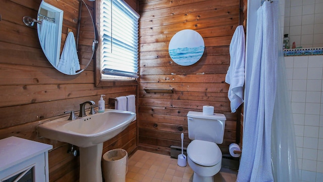 bathroom with wooden walls, sink, and toilet