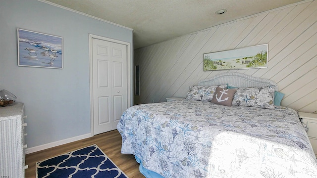 bedroom with wood walls, dark wood-type flooring, and a closet