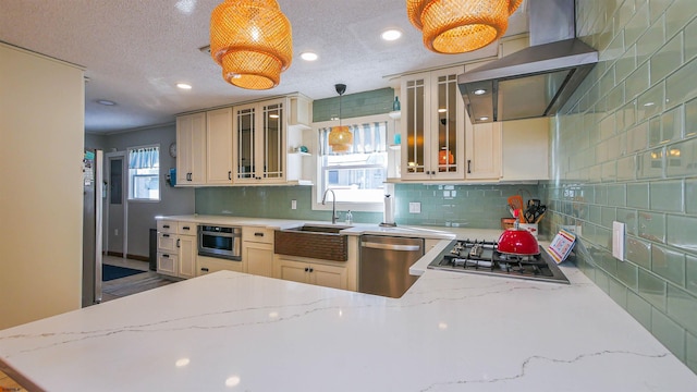 kitchen featuring pendant lighting, ventilation hood, sink, a textured ceiling, and appliances with stainless steel finishes