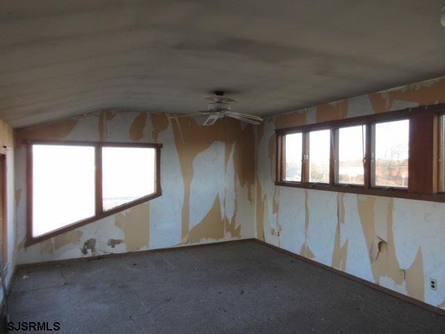 carpeted spare room featuring lofted ceiling and ceiling fan