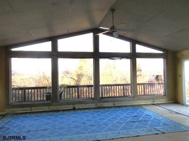 unfurnished sunroom with lofted ceiling and ceiling fan