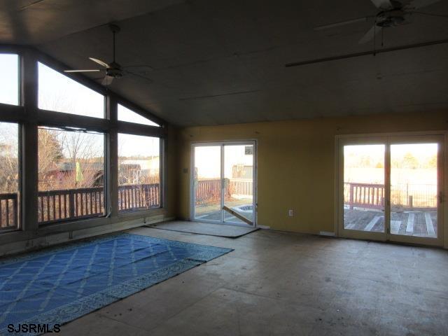 unfurnished sunroom featuring ceiling fan