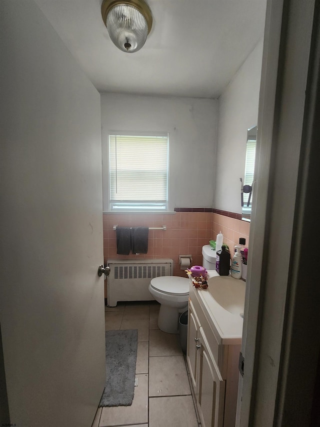 bathroom featuring tile patterned flooring, tile walls, toilet, radiator heating unit, and vanity