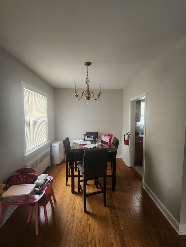 dining room with a notable chandelier, radiator heating unit, and wood-type flooring