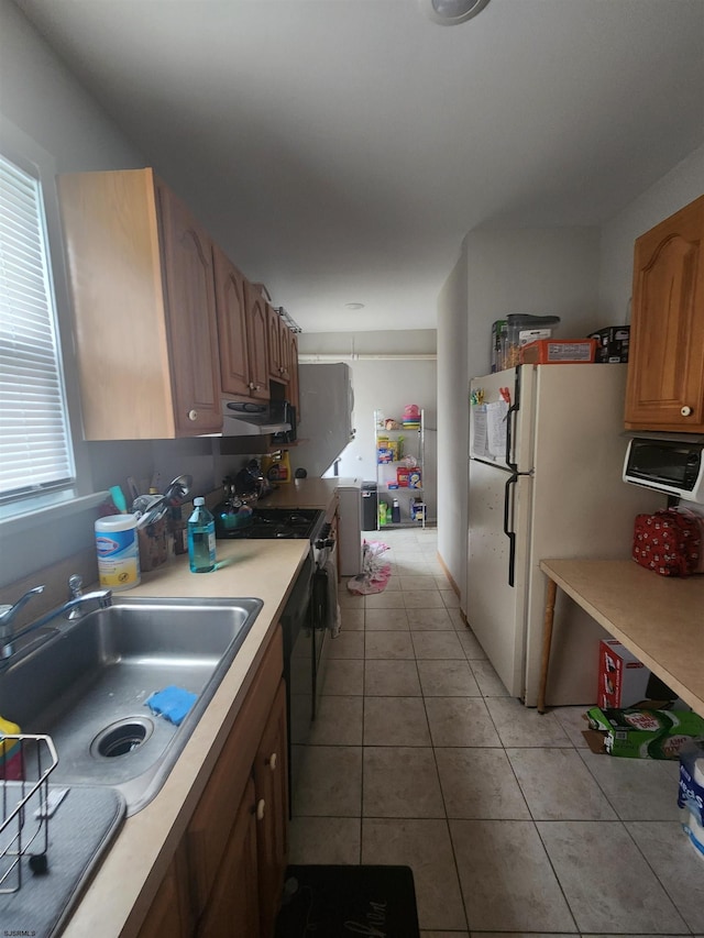 kitchen featuring white refrigerator, light tile patterned floors, stove, and sink