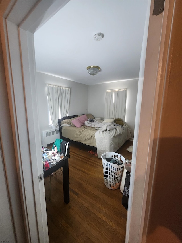 bedroom with dark hardwood / wood-style flooring and radiator heating unit