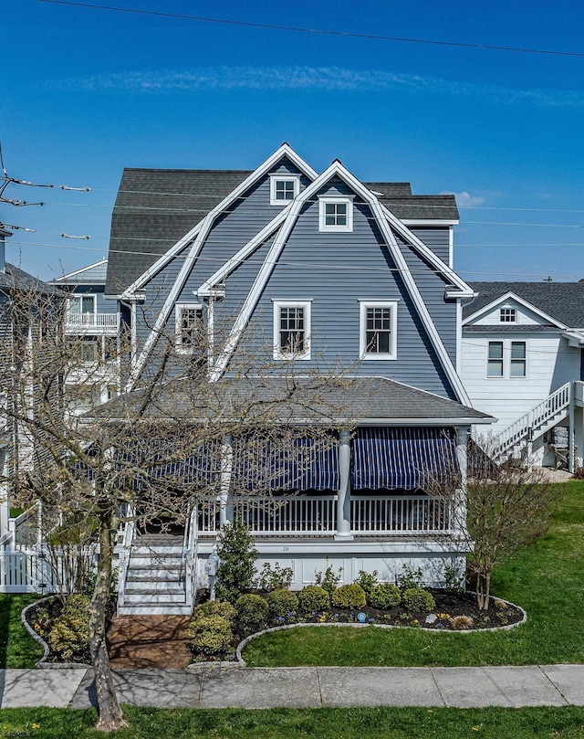 shingle-style home featuring stairs, roof with shingles, and a gambrel roof