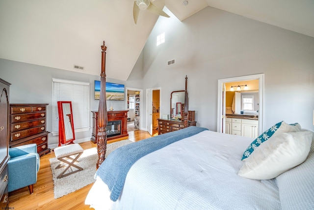 bedroom with connected bathroom, high vaulted ceiling, ceiling fan, and light hardwood / wood-style floors