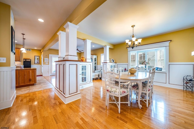 dining space featuring a notable chandelier, light hardwood / wood-style flooring, and ornate columns