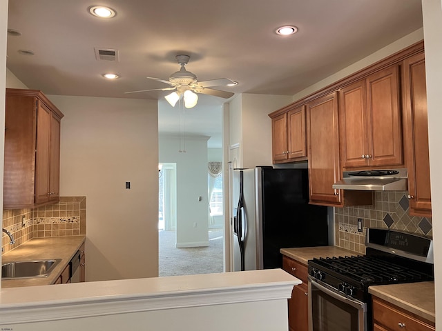 kitchen with stainless steel appliances, sink, ceiling fan, kitchen peninsula, and backsplash