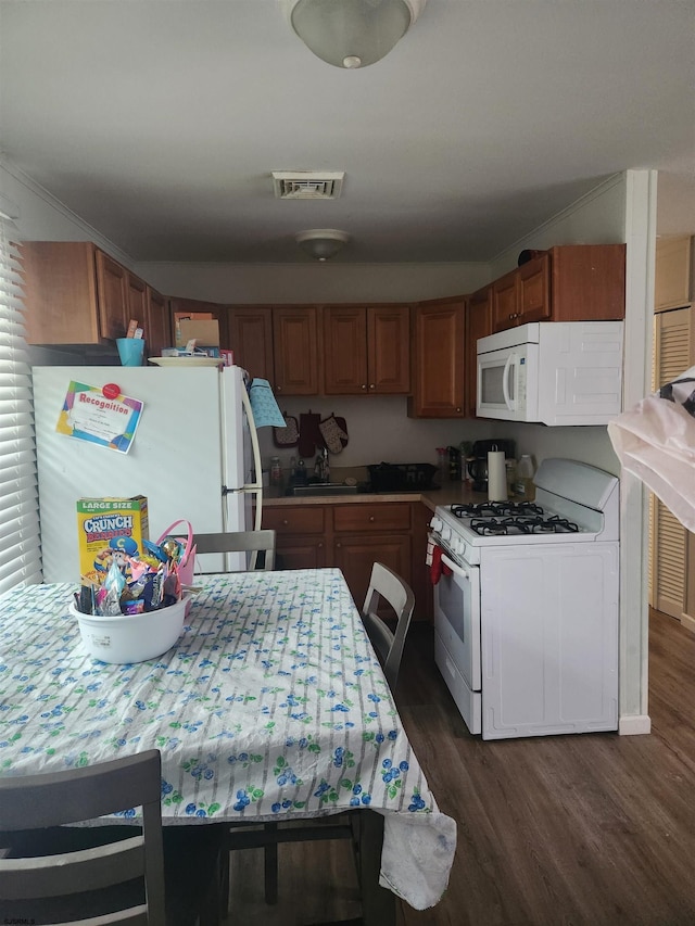 kitchen with white appliances, dark wood-type flooring, and ornamental molding