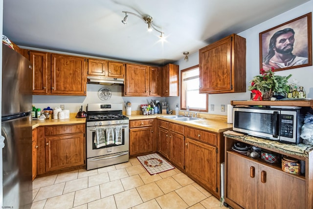 kitchen featuring sink, rail lighting, light tile patterned floors, and appliances with stainless steel finishes