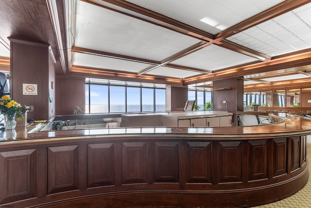 kitchen with coffered ceiling, crown molding, and dark brown cabinetry