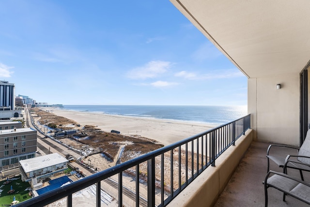 balcony with a water view and a view of the beach