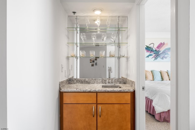 bar featuring light stone countertops, light carpet, and sink