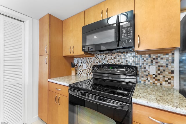 kitchen featuring backsplash, light stone countertops, and black appliances