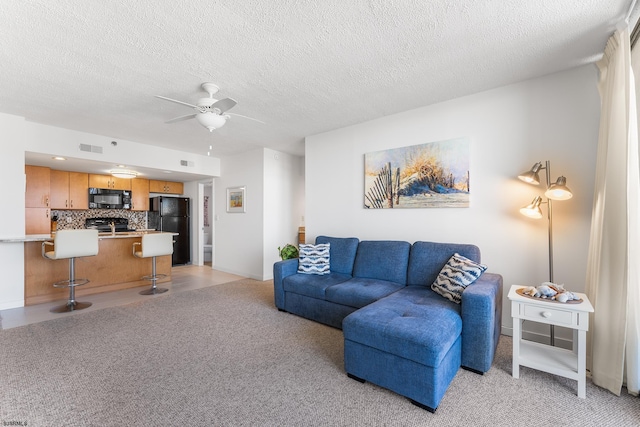 carpeted living room with ceiling fan and a textured ceiling