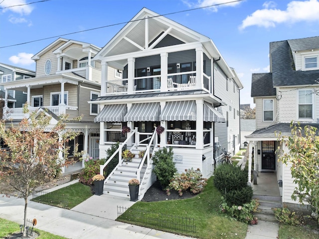 view of front of home with covered porch, a balcony, and a front lawn