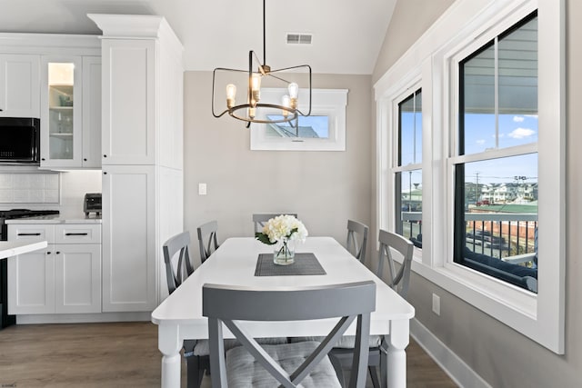 dining room with lofted ceiling, hardwood / wood-style flooring, and a chandelier