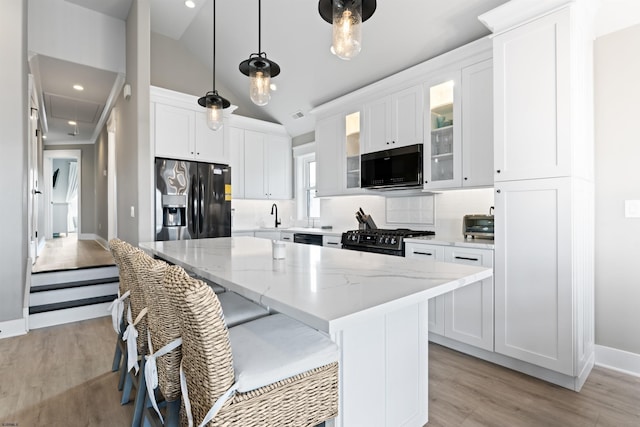 kitchen with white cabinets, a center island, and black appliances